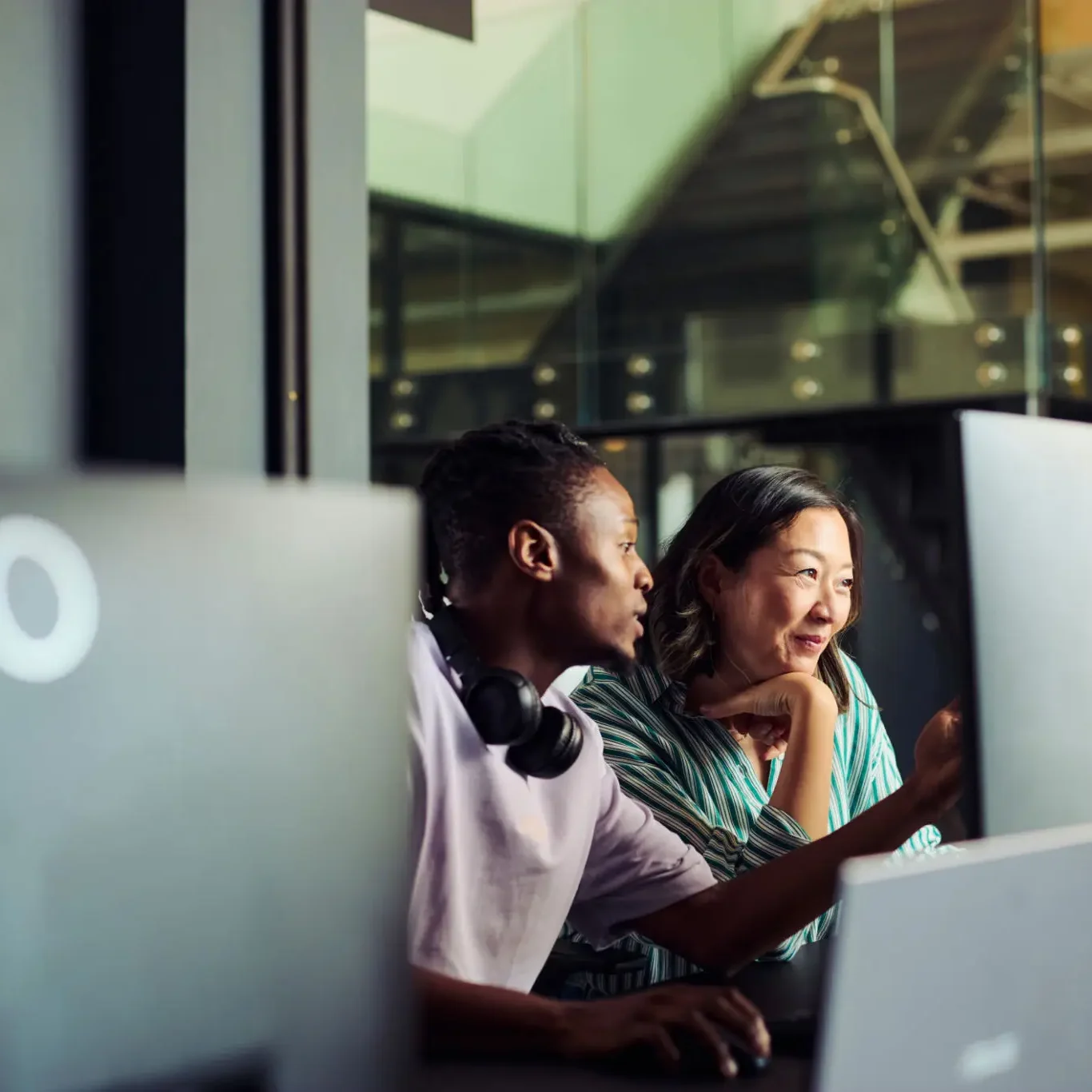 Two coworkers collaborating at office computers