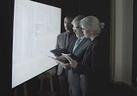 Three professionals reviewing data on illuminated screen
